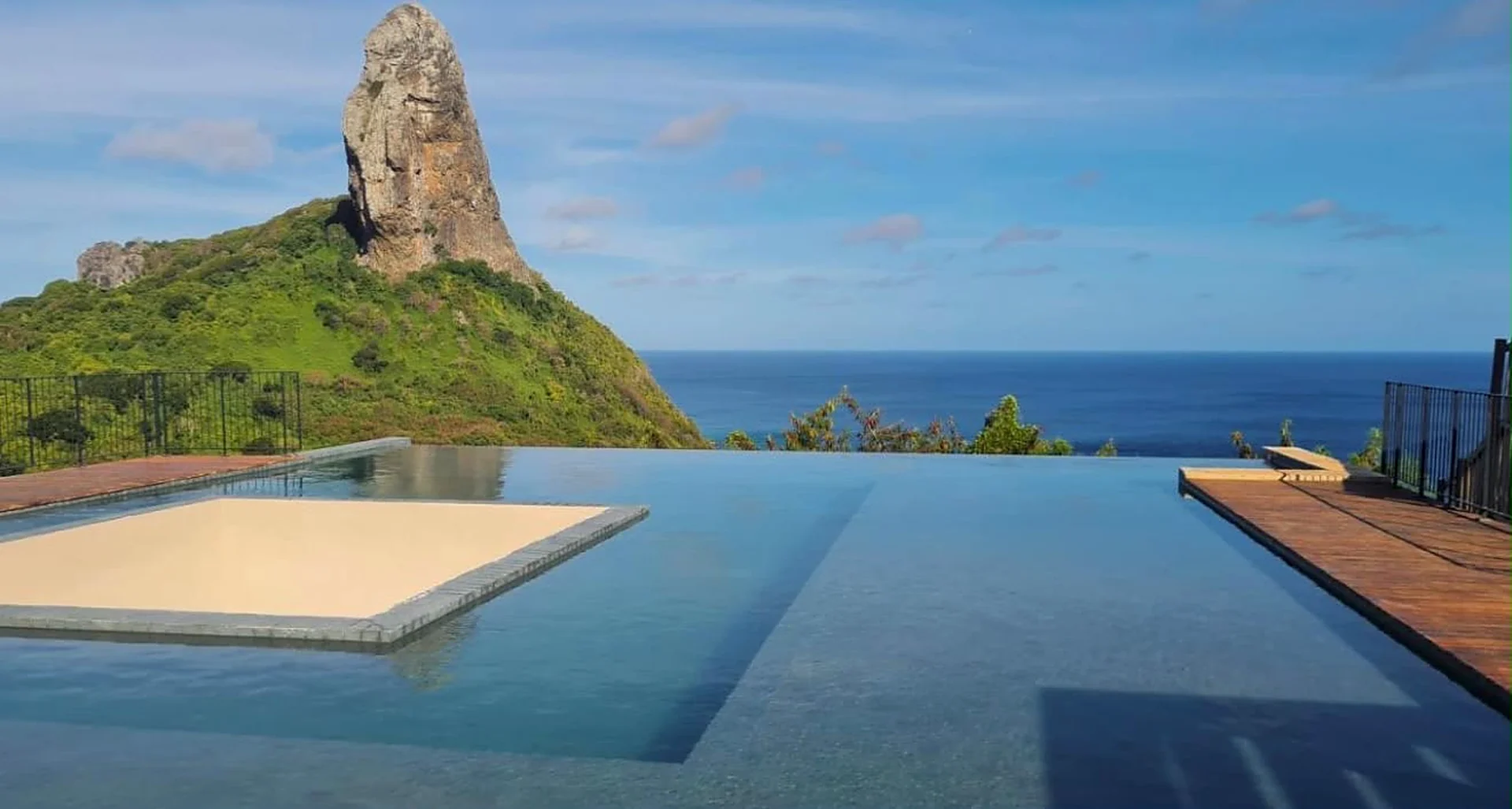 Piscina de borda infinita com o Morro do Pico ao fundo